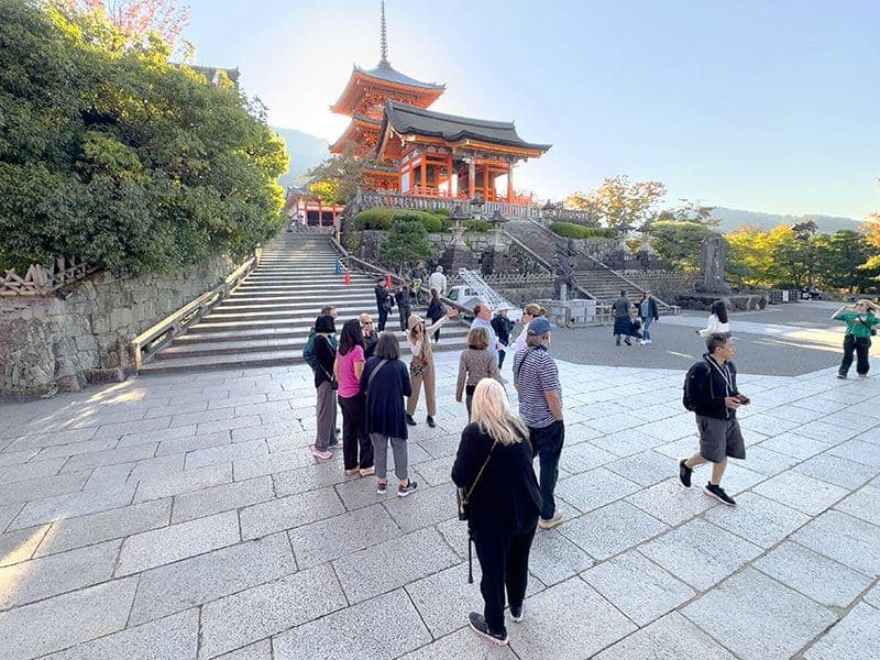 people looking at a red temple on a hill