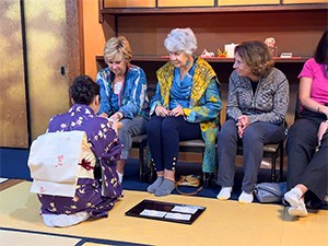 three women looking at a woman serving them tea