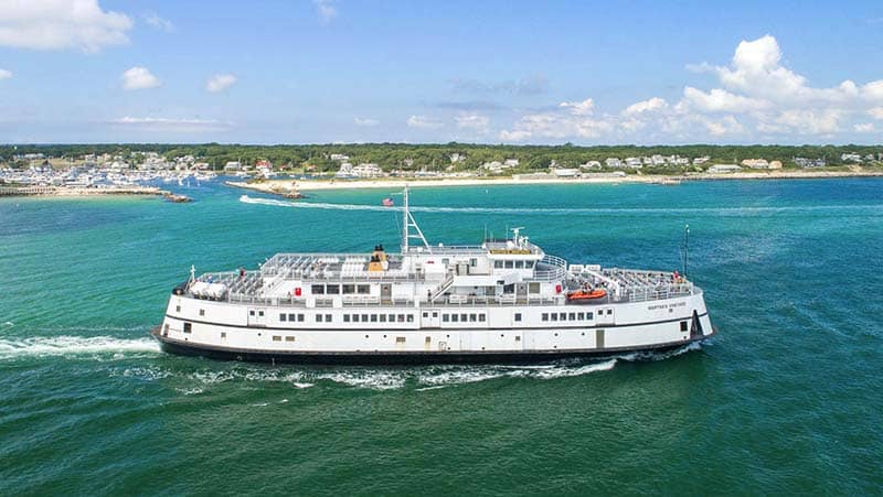 a large ferry sailing past a town - nantucket vs marthas vineyard