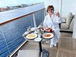 woman in a while robe having breakfast of a stateroom balcony