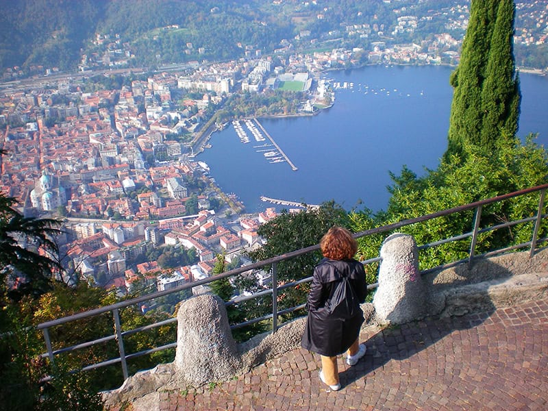 a woman looking down on Lake Como from a path high above