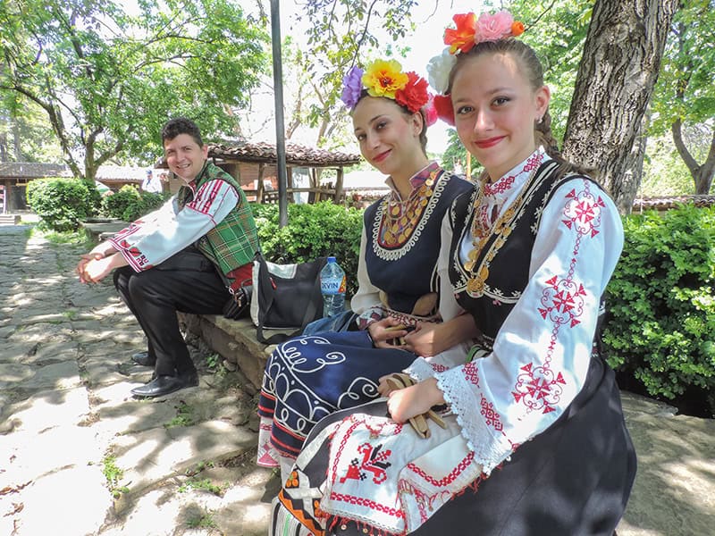 two women and a man in folk costumes waiting to perform at a Eastern European Festivals