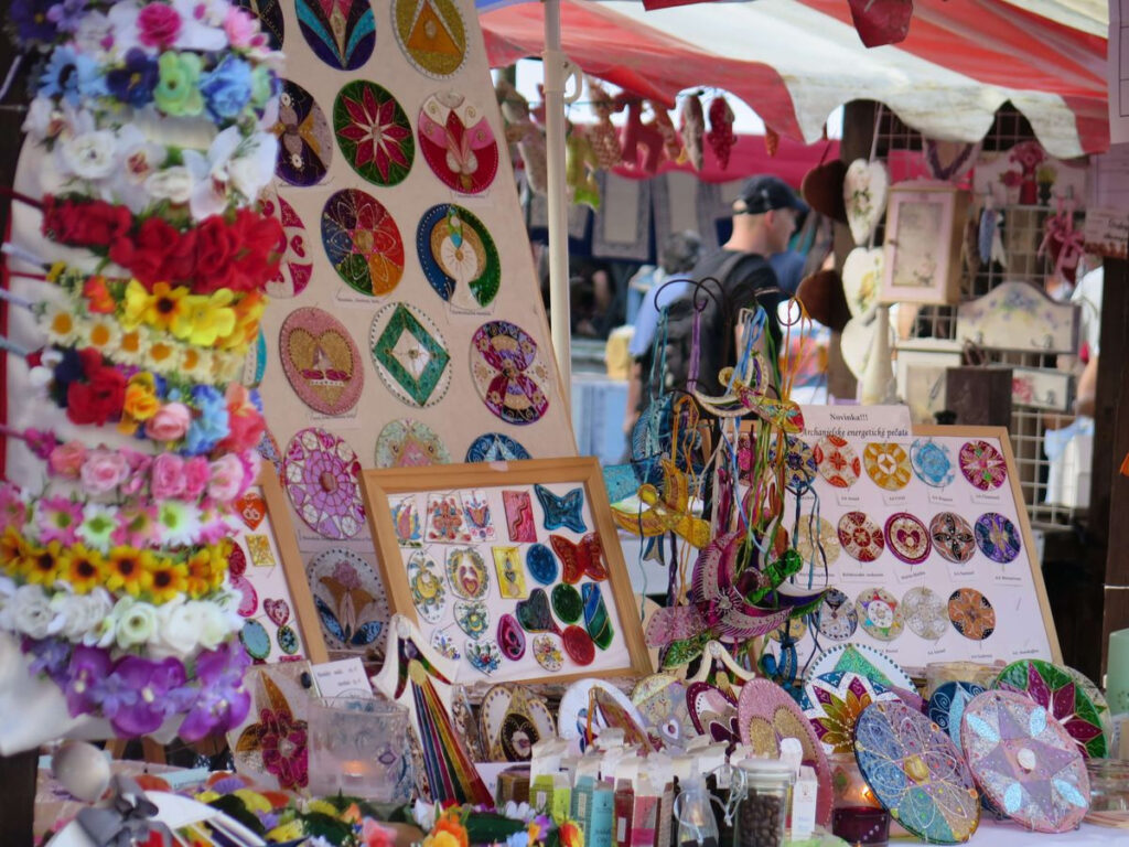 people walking by a festive stand with handcrafts for sale