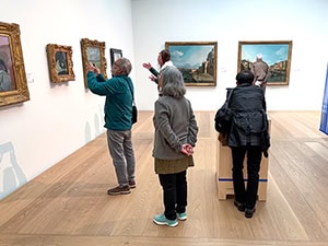 people pointing at paintings in a museum