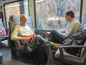 two young men sitting on a train reading books