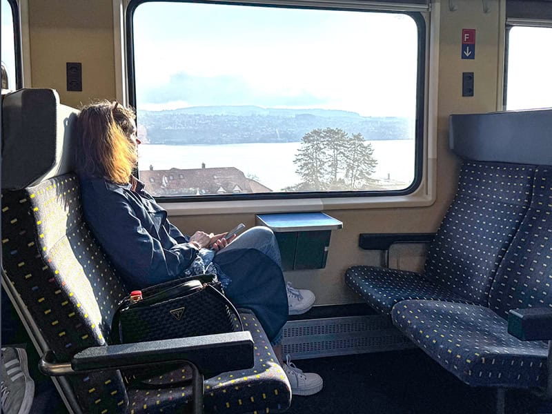 A woman looking out a train window en route to enjoy 3 days in Zurich
