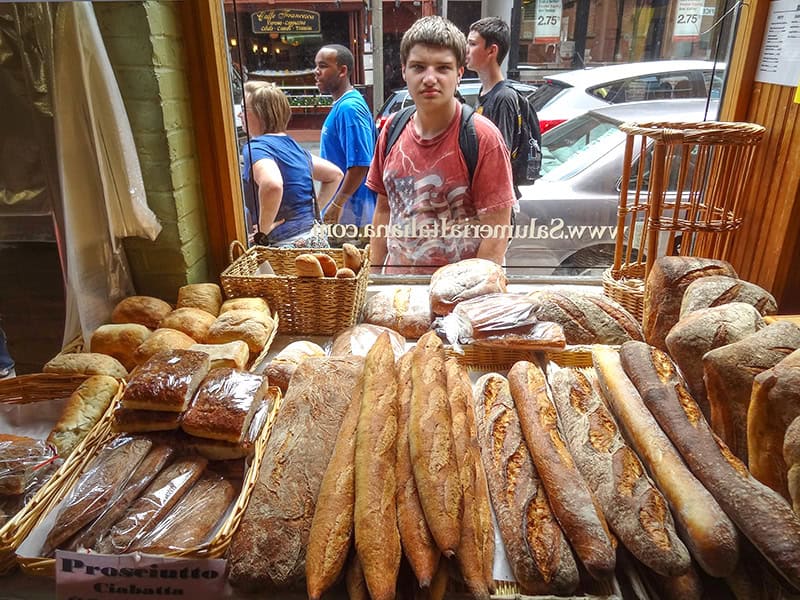 a boy looking at bread loaves in a bakery window