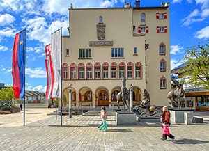 people walking by a building with statues in front