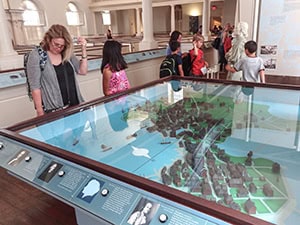 people looking at a diorama of old Boston 