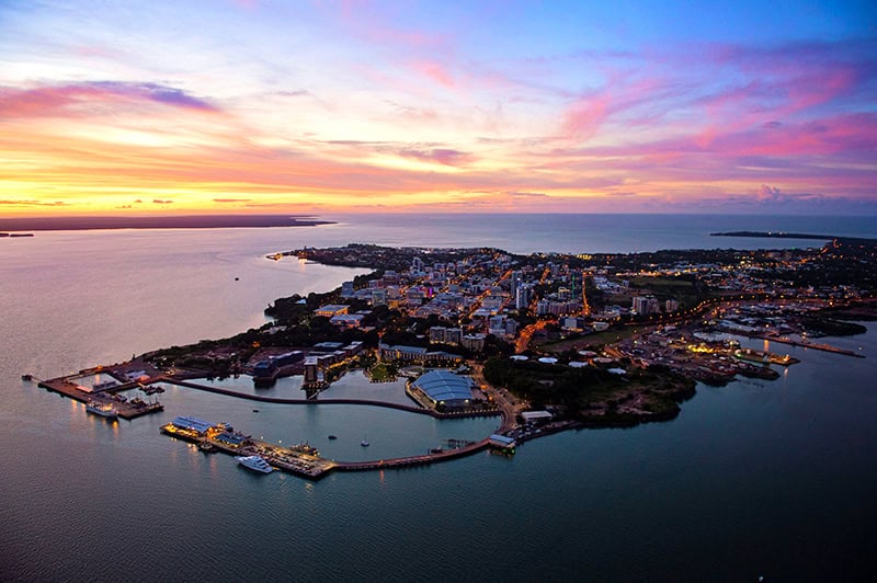 sunset over a city on the ocean in the northern territory australia