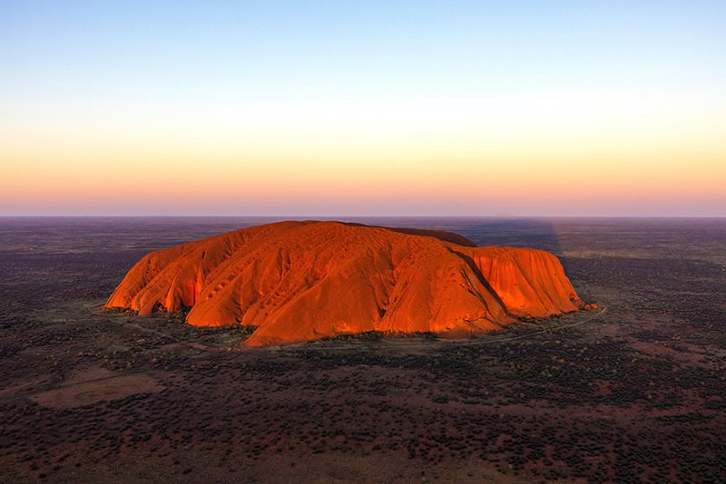 a huge red rock at sunset