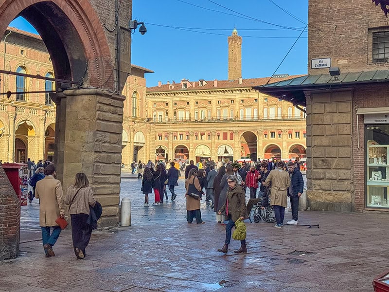 people walking past ancient buildings in Bologna Italy