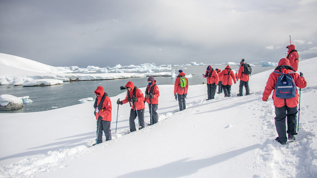 people in red jackets walking through snow on a cruise to Antarctica