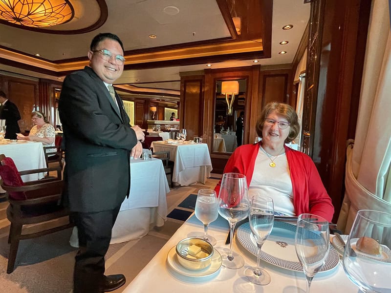 a woman and a man in an ornate dining room on a Cunard queen Elizabeth Caribbean cruise 