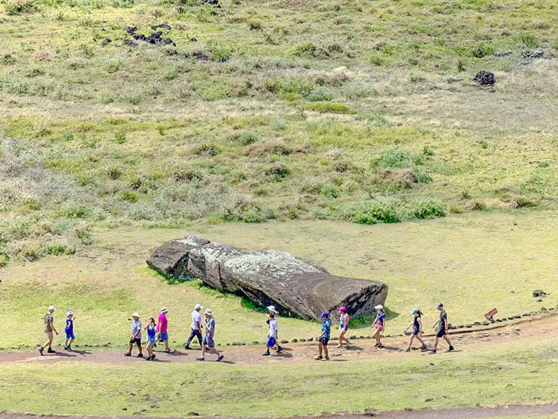people walking by a toppled statue on Easter Island Chile
