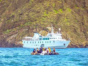 people in a small boat near a yacht