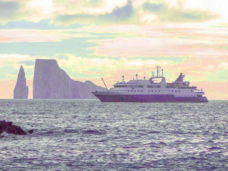 a ship sailing by a huge rock in the Galapagos Islands