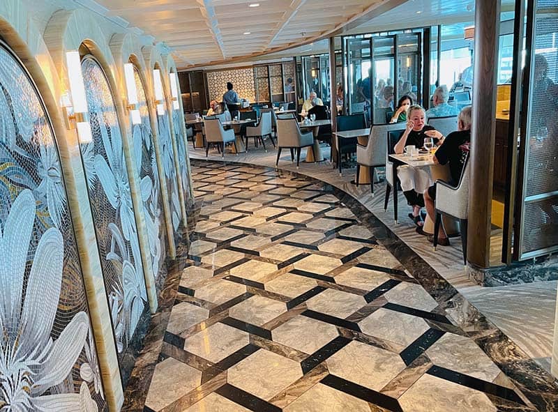 people sitting at tables along a hallway with a marble floor