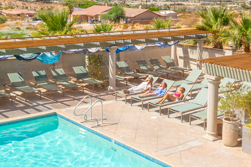 3 women sun bathing by a pool in Greater Palm Springs